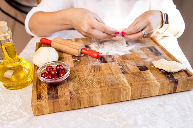 Hands preparing dough on wooden board